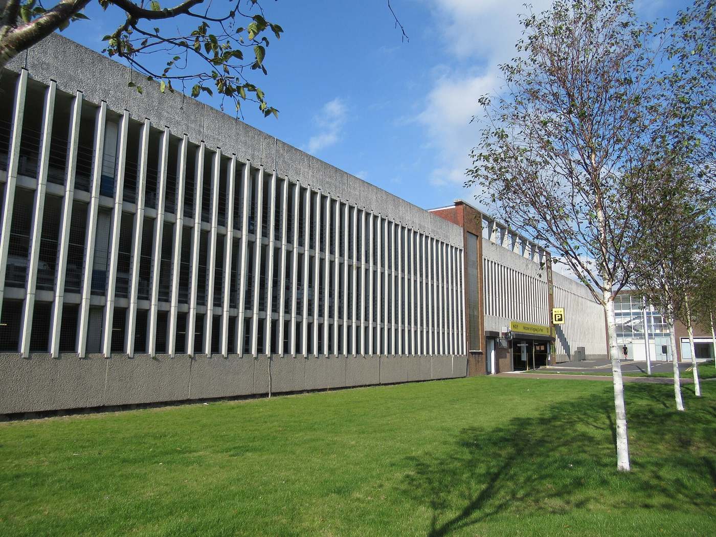 Long modernist concrete building facade with vertical concrete fins under a blue sky
