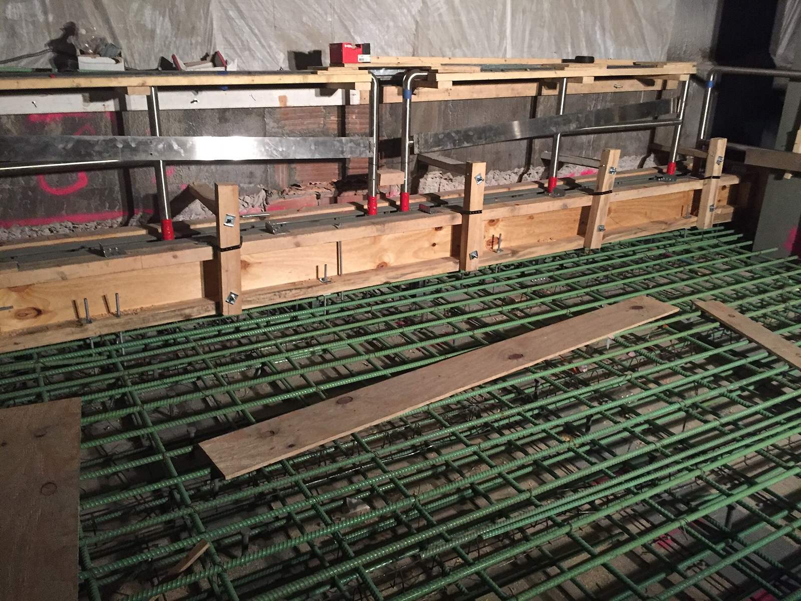 Grid of epoxy-coated rebar tied over a slab deck with timber edge forms, ready for a concrete pour